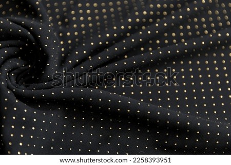 Defocused blurred golden polka dot pattern on black folded fabric as background