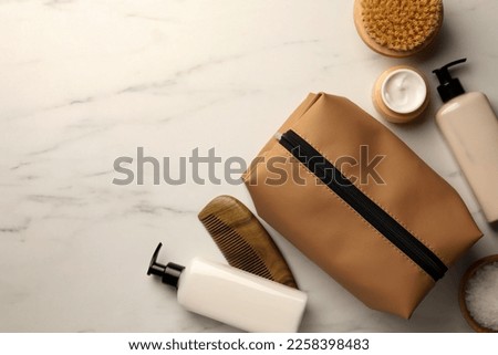 Preparation for spa. Compact toiletry bag and different cosmetic products on white marble table, flat lay with space for text Royalty-Free Stock Photo #2258398483