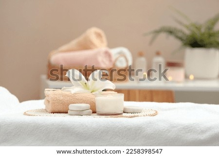 Beautiful spa composition with burning candle and stones on massage table in wellness center. Space for text