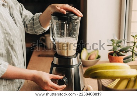 Woman blending spinach, berries, bananas and almond milk to make a healthy green smoothie Royalty-Free Stock Photo #2258408819