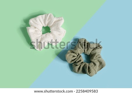 Two stylish scrunchies on color background