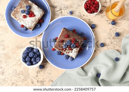 Plates with pieces of cottage cheese casserole and berries on light background