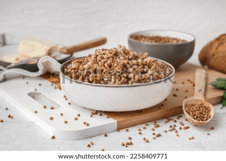 Board with bowl of tasty buckwheat porridge on white table Royalty-Free Stock Photo #2258409771