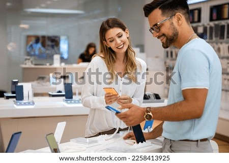 Shopping a new digital device. Happy couple buying a smartphone in store. Royalty-Free Stock Photo #2258413925