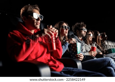 A group of friends are watching a movie with 3D glasses. Selective focus in the center of the photo