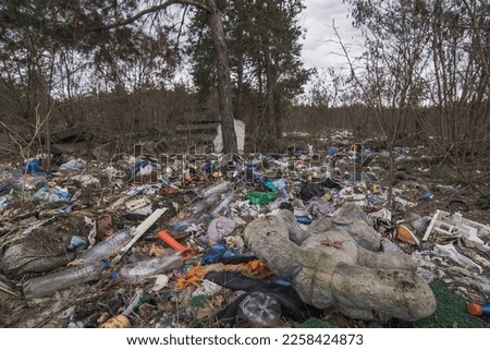 Illegal dumping in forest landscape photo. Negative environmental impact nature photography with blurred background. Trash scene. High quality picture for wallpaper, travel blog, magazine, article