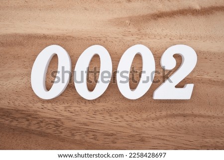 White number 0002 on a brown and light brown wooden background.
