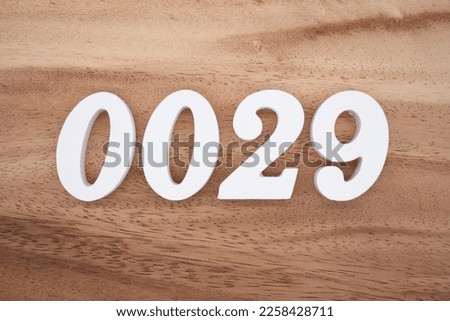 White number 0029 on a brown and light brown wooden background.