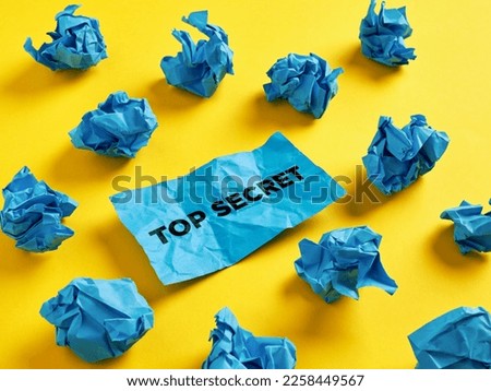Seeking, revealing or finding the top secret confidential information. The word top secret on piece of paper among the crumpled blue paper balls. Royalty-Free Stock Photo #2258449567