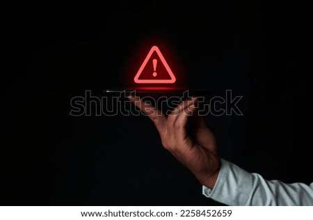 Hand holding smartphone with warning triangle sign for error alert and maintenance concept. Data protection from hackers Royalty-Free Stock Photo #2258452659