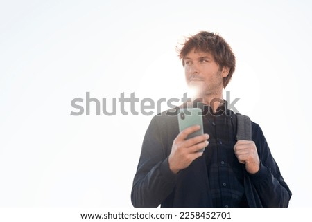 Stock photo of handsome man using his cellphone in the street.