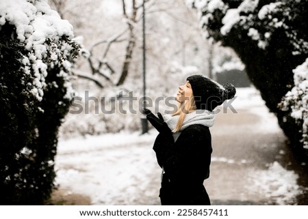 Pretty young woman in warm clothes enjoying in snow
