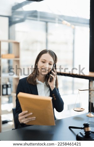 Portrait of a Asian woman lawyer studying lawsuit a for a client using smartphone , documents and computer  to work before going to court
