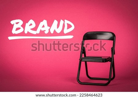 BRAND, business concept. Black chair on a pink background.