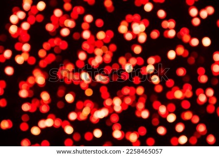 Red defocused light confetti on a black background. Bicolor bokeh background