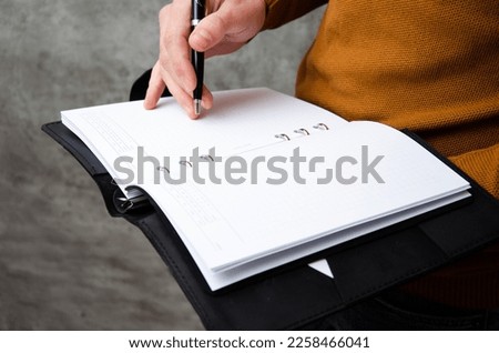A man writes a plan in a notebook on a gray background with concrete texture. Lifestyle.