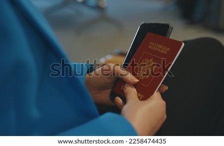 Woman with Russian Federation passport is waiting for her flight at the airport. Royalty-Free Stock Photo #2258474435