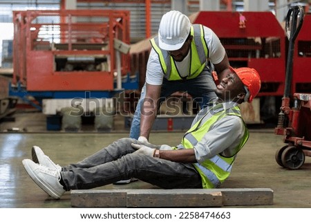 Industrial accident concept. Male african american accidents from working carrying heavy objects on legs in Industrial factory. Royalty-Free Stock Photo #2258474663