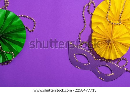 Festive Mardi Gras masquerade purple background. Fat Tuesday carnival, masks, beads, traditional decor. Symbolic colors, trendy hard light, dark shadow, flat lay, top view