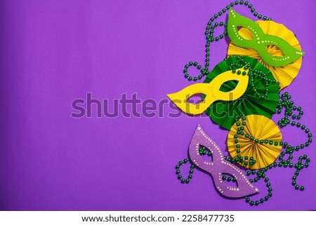 Festive Mardi Gras masquerade purple background. Fat Tuesday carnival, masks, beads, traditional decor. Symbolic colors, trendy hard light, dark shadow, flat lay, top view