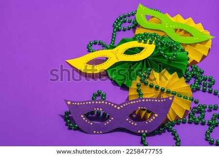 Festive Mardi Gras masquerade purple background. Fat Tuesday carnival, masks, beads, traditional decor. Symbolic colors, trendy hard light, dark shadow, flat lay, copy space