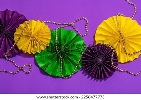 Festive Mardi Gras masquerade purple background. Fat Tuesday carnival, beads, traditional decor. Symbolic colors, trendy hard light, dark shadow, flat lay, top view