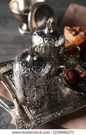 Tea, Turkish delight and date fruits served in vintage tea set on grey textured table, closeup