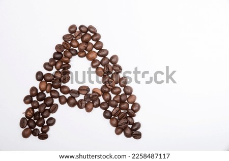 A is a capital letter of the English alphabet made up of natural roasted coffee beans that lie on a white background. Plenty of space to put text or pictures, top view and studio photography.