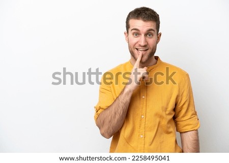 Young caucasian man isolated on white background showing a sign of silence gesture putting finger in mouth