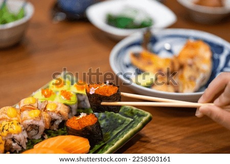 Taking tobiko (fish egg) sushi with chopstick.
Eating sushi platter.