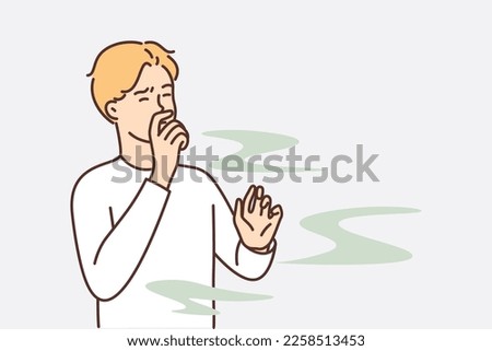 Man covers nose so as not to smell unpleasant smell from harmful production that pollutes environment. Guy grimaces and closes eyes, feels vile stench coming from missing products or garbage dump Royalty-Free Stock Photo #2258513453