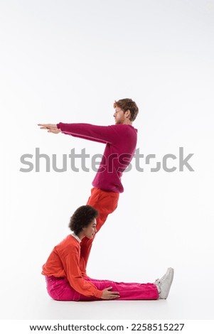 side view of interracial man and woman in magenta color clothes showing z letter on white background