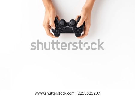 Woman’s hands playing video game controller over white background with copyspace. Top view Royalty-Free Stock Photo #2258525207