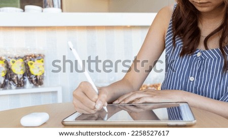 Young woman holding a stylus in her hand to use along with application in tablet to test and develop ux ui system and to design application that can work efficiently with perfect ux ui system.