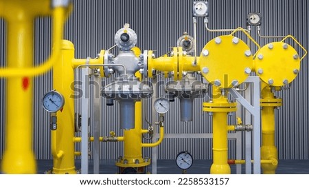 Gas equipment close-up. Compressor station with pressure gauges. Gas equipment inside factory building. Yellow pipes on metal supports. Supply of production with natural gas.  Royalty-Free Stock Photo #2258533157