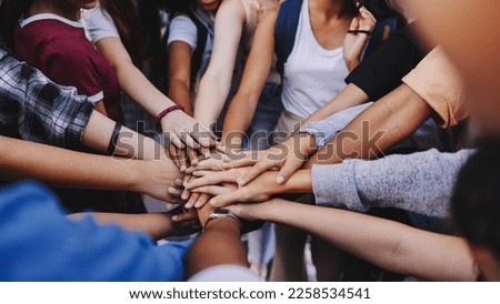 Multicultural teenagers putting their hands together in a huddle. Group of unrecognizable young people expressing their unity and teamwork Royalty-Free Stock Photo #2258534541