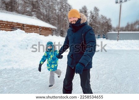 young caucasian bearded man skating with his son, holding hands. Father's day concept. Image with selective focus. High quality photo