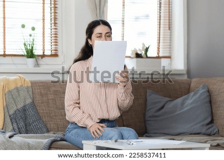 Purchase of real estate. Young caucasian woman sitting on sofa and reading documents. Concept of leasing, business and mortgage.