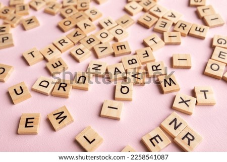 Top view of square wooden tiles with the English alphabet lying on a pink background. The concept of developing thinking, grammar, back to school, learning.