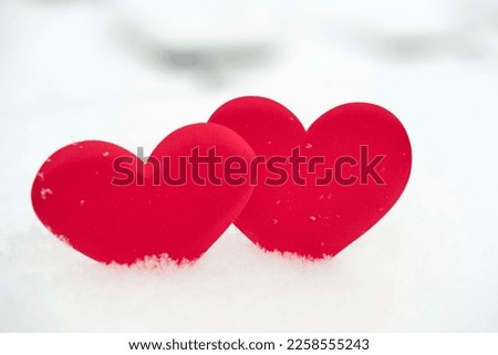 Two red heart shape on natural pure white soft snow surface side by side. Symbol of love in winter holiday season. Romantic outdoor concept for Valentine's day with copy space. front view, close up