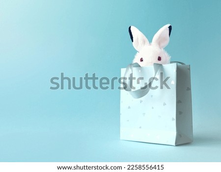 Easter bunny in a paper bag. White Rabbit. Blue background. Space for text. Happy easter