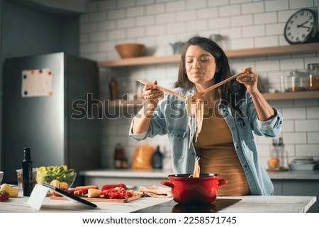 Beautiful pregnant woman preparing delicious food. Smiling woman cooking at home.	 Royalty-Free Stock Photo #2258571745