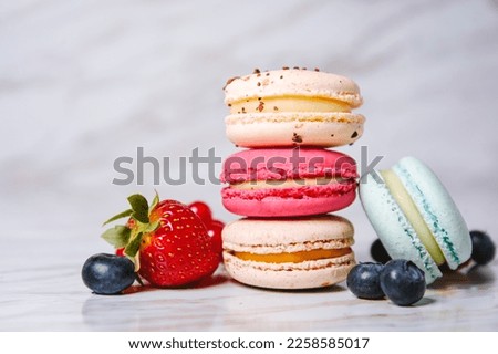 Macaron pink, orange and beige, blue on marble style. A beautiful and beautiful French dessert. Fruits, Strawberries and lingonberries, blueberries, raspberries Royalty-Free Stock Photo #2258585017