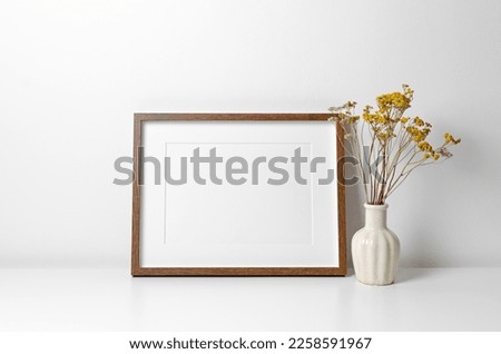 Landscape picture frame mockup in white minimalistic interior with dry flowers decor