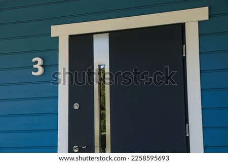 Number three on blue wooden house near stylish door outdoors