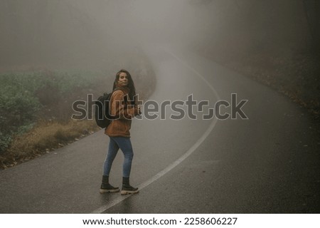 Hiker woman photographer walking and exploring through the misty nature. Copy space.