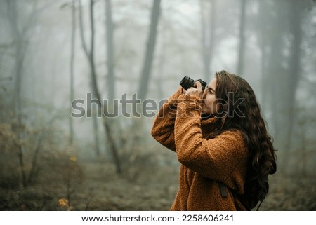 Beautiful woman taking pictures outdoors with a digital camera. Woman taking a photos and exploring the nature 