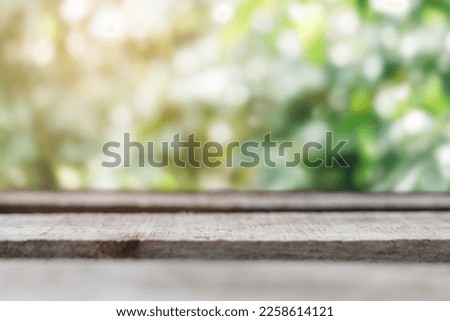 wood table on blur garden background with light flare.