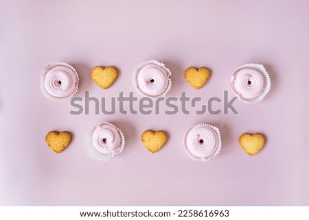 in the center on a pink background are heart-shaped cookies and pink marshmallows in order