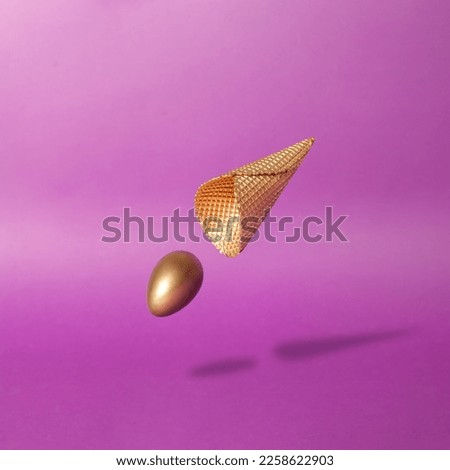 Surreal scene with golden egg and ice cream cone against deep purple background. Creative easter composition.